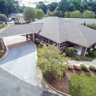 Aerial view of a building with surrounding greenery and a driveway.