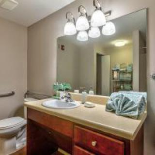 A well-lit bathroom with a vanity, mirror, and neatly arranged towels.