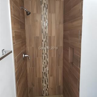 A modern shower with wood-like tiles and a mosaic accent.