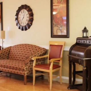 A cozy living room with a patterned sofa, a wooden chair, and an antique-style desk.