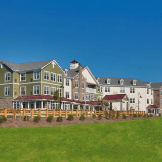 A picturesque view of a multi-story residential building with a grassy foreground and clear blue sky.