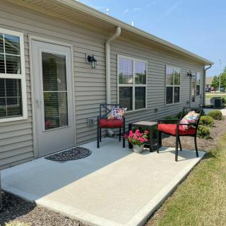 A cozy patio with red-cushioned chairs and a small table set against the house exterior.