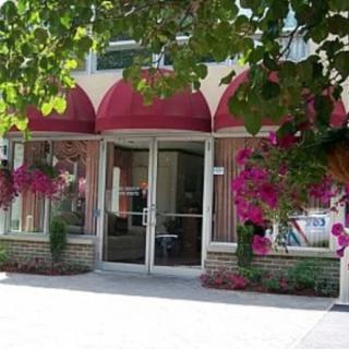 A quaint storefront with a red awning and vibrant flower arrangements adorning the entrance.