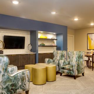 A modern living room with patterned armchairs, a flat-screen TV, and stylish shelving.