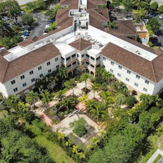 Aerial view of a residential building surrounded by lush greenery and landscaped gardens.