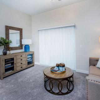 A modern living room featuring a comfortable sofa, stylish coffee table, and decorative elements including a large mirror and lamp.