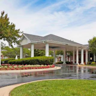 An elegant building entrance with white columns and well-maintained landscaping.