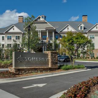 A view of a residential building with a landscaped entrance and signage.