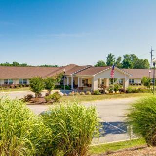 A sunny day view of a building with a landscaped lawn and driveway.