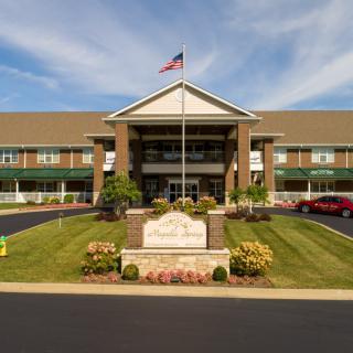 A front view of a building with an American flag, well-maintained landscaping, and a clear sky.
