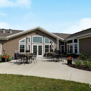 A spacious backyard patio area with outdoor seating, surrounded by a landscaped garden and featuring large windows.