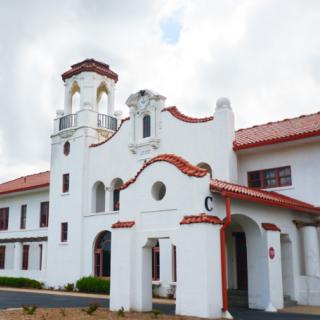 A historic colonial-style building with a white facade and red roof, featuring a prominent tower.