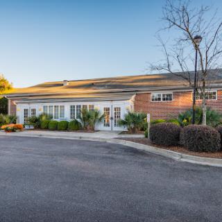 A picturesque view of a modern building surrounded by landscaped greenery and a clear blue sky.