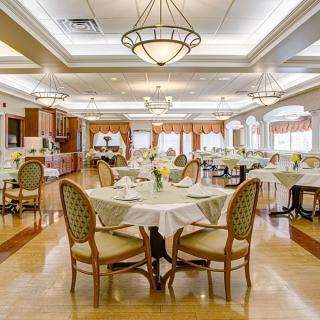 An elegantly designed dining room with well-arranged tables and chairs, illuminated by chandeliers.