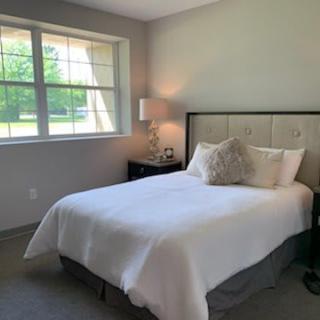 A cozy bedroom with a neatly made bed and a lamp by the window.