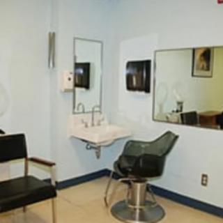 A small hair salon setup with a sink, mirror, and barber chairs.