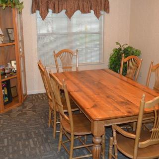 Cozy dining room with a wooden table and chairs, complemented by a bookshelf and indoor plant.