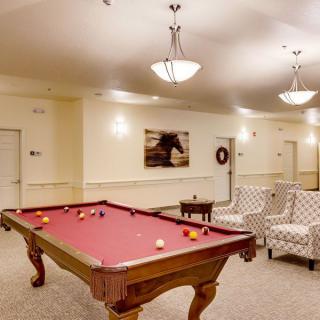 A cozy game room featuring a pool table with red felt and comfortable seating.