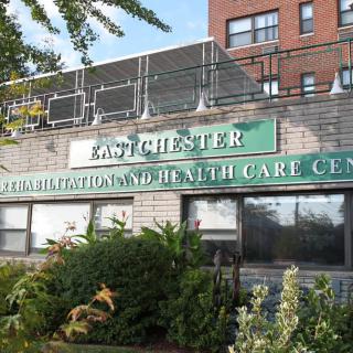 Exterior view of a health care and rehabilitation center with signage surrounded by greenery.