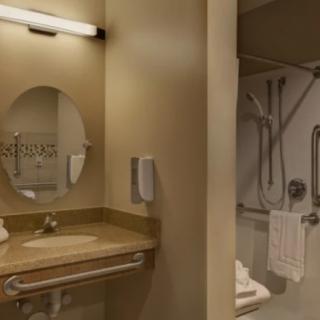 Accessible bathroom with mirror, sink, and grab bars.