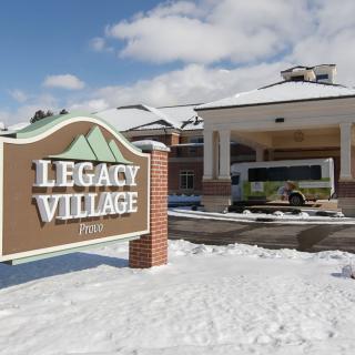 A winter scene featuring the Legacy Village building and sign, surrounded by snow.