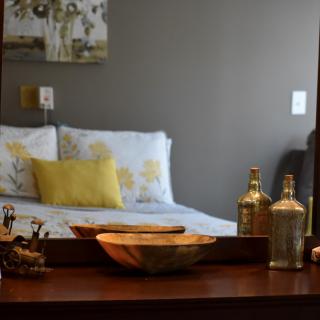 A cozy bedroom view with a bed reflected in the mirror, adorned with pillows and decorative items.