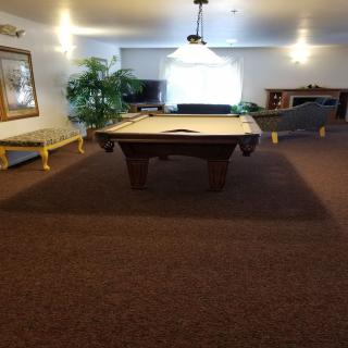 A spacious recreation room featuring a pool table, comfortable seating, and a television.