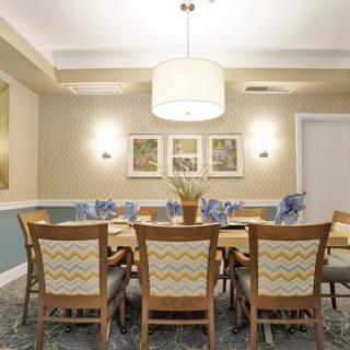 A well-decorated dining room featuring a wooden table with matching chairs, adorned with elegant decor and illuminated by a ceiling light.
