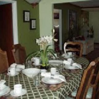 A dining room with a set table, featuring a green tablecloth and floral centerpiece.