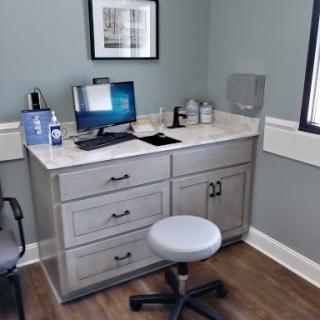 A modern medical office workspace featuring a desk with a computer and ergonomic chair.