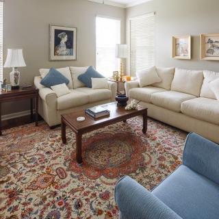 A cozy living room with two beige sofas, a wooden coffee table, and a patterned carpet.