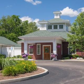 A charming small building with a landscaped garden and driveway in front.