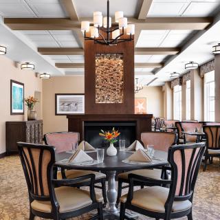 An elegant dining room with a central fireplace and stylish furnishings.