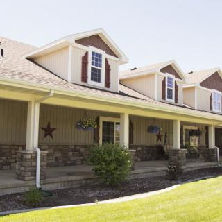 A suburban house with a large porch and a well-maintained lawn.