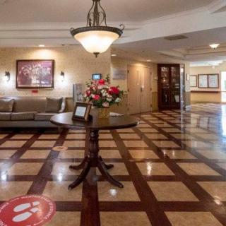 A spacious lobby with elegant decor, featuring a central table with flowers, comfortable seating, and decorative lighting.
