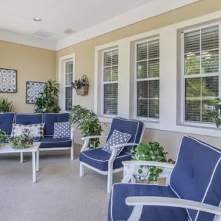 A cozy patio seating area with blue cushioned chairs, decorated with plants and artwork.