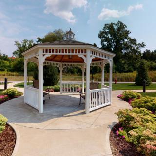 A picturesque white gazebo surrounded by a landscaped garden and paved pathways.