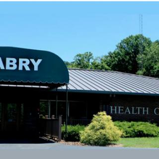 A health center building with a green awning and landscaped surroundings.