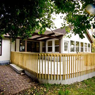 A charming house with a wooden deck surrounded by lush trees.