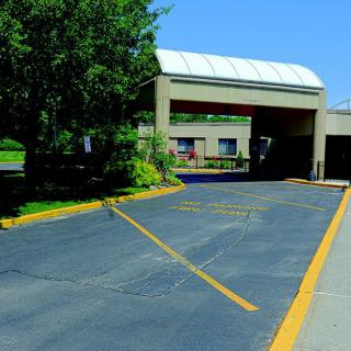 A drive-thru area outside a building with surrounding trees.