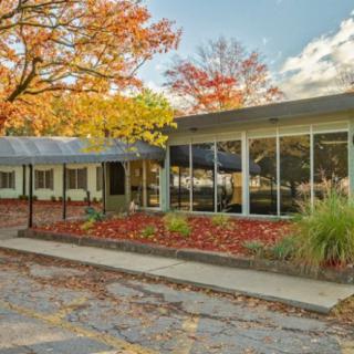 A mid-century modern building surrounded by vibrant autumn foliage.
