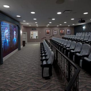A modern auditorium with rows of seats and a large screen at the front.