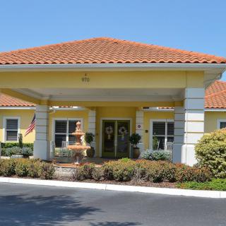A well-maintained building entrance with a covered driveway and landscaped surroundings.