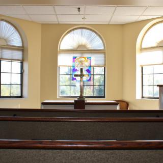 Interior view of a chapel featuring stained glass windows and wooden pews.