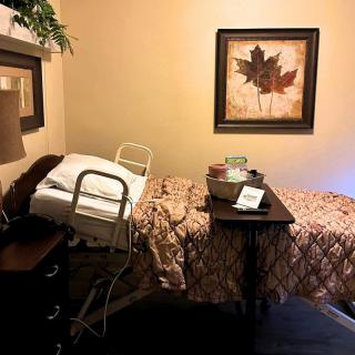 A cozy bedroom with a bed, nightstand, lamp, and framed artwork on the wall.