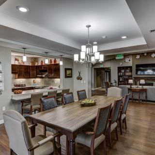A modern open concept dining area connected to a kitchen with elegant lighting and furnishings.