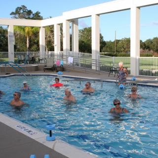 Group of people participating in a water aerobics class in an outdoor swimming pool.