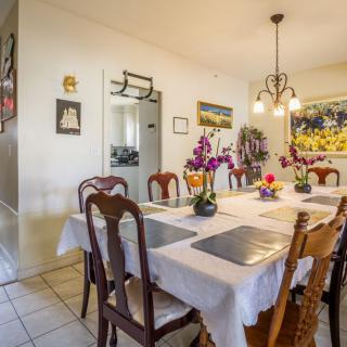 A well-decorated dining room with a table set with flowers and placemats under a chandelier.