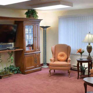 A cozy living room with an armchair, wooden bookshelf, and a television.