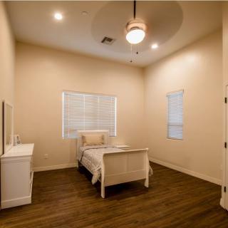 A minimalist bedroom with a single bed, nightstand, and wooden flooring.